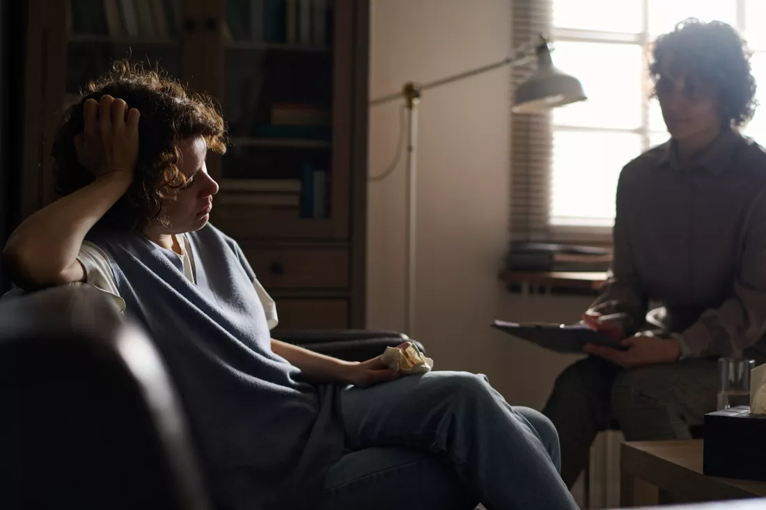 sad-young-brunette-female-patient-counselor-with-tissue-sitting-couch