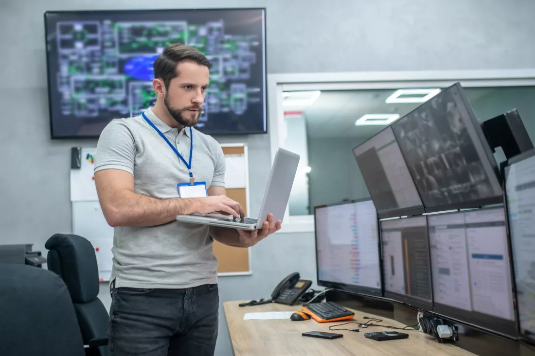 attention-focus-attentive-young-muscular-man-with-badge-laptop-standing-front-computer-monitors